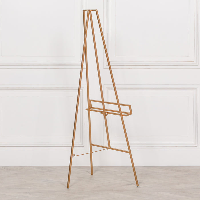Side view of bright gold metal easel showcasing adjustable shelf and sleek design

