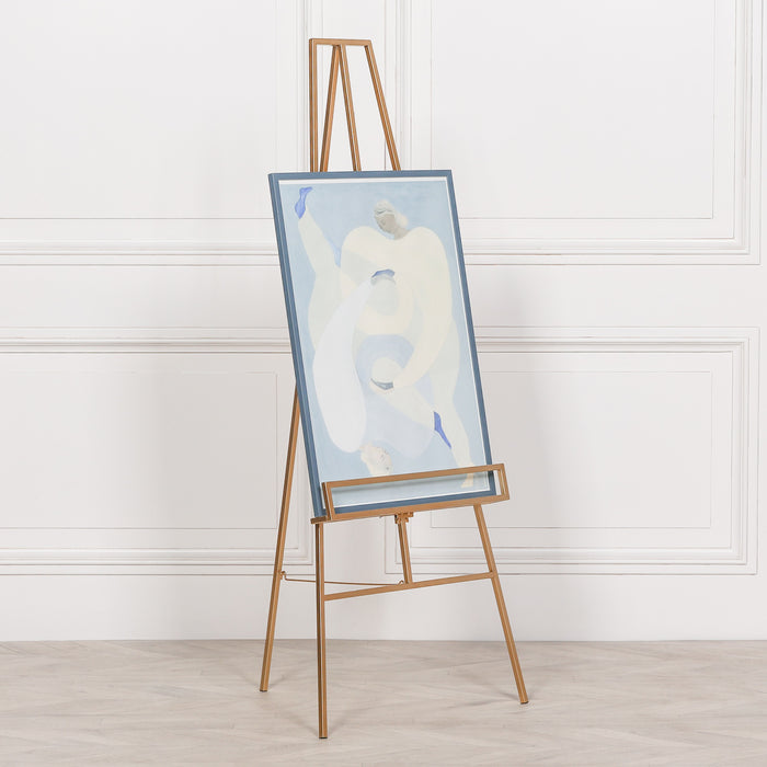 Adjustable bright gold metal easel holding framed artwork in gallery setting

