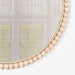 Close-up of gold-painted bobble edge detailing on round wooden wall mirror


